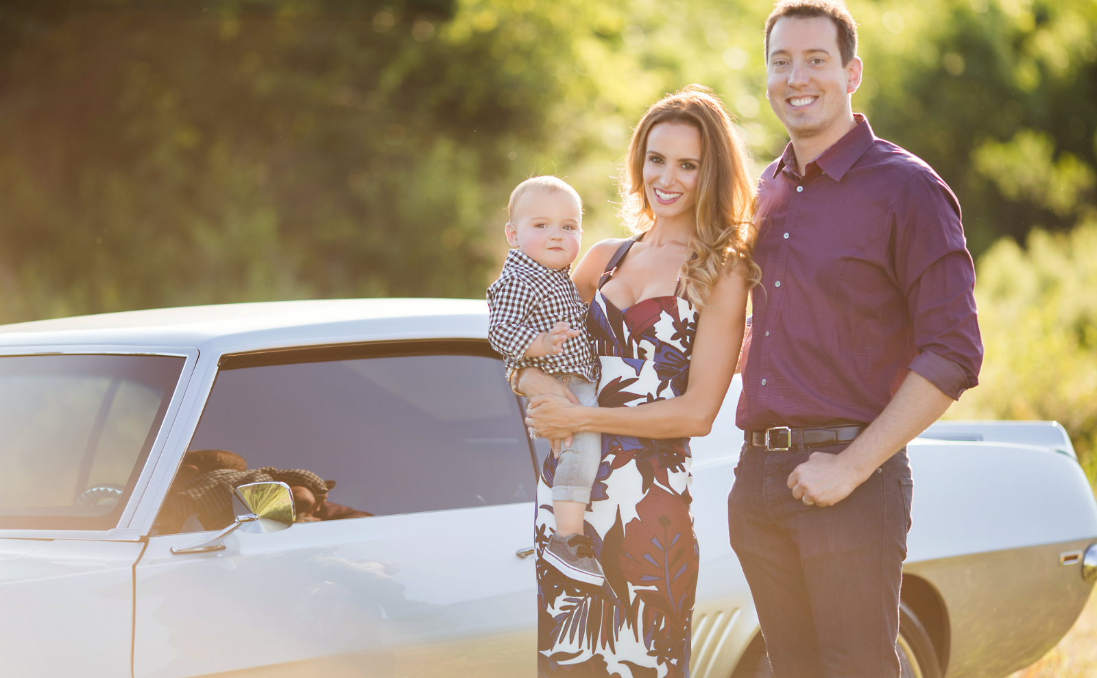 kyle and samantha busch next to muscle car holding child 