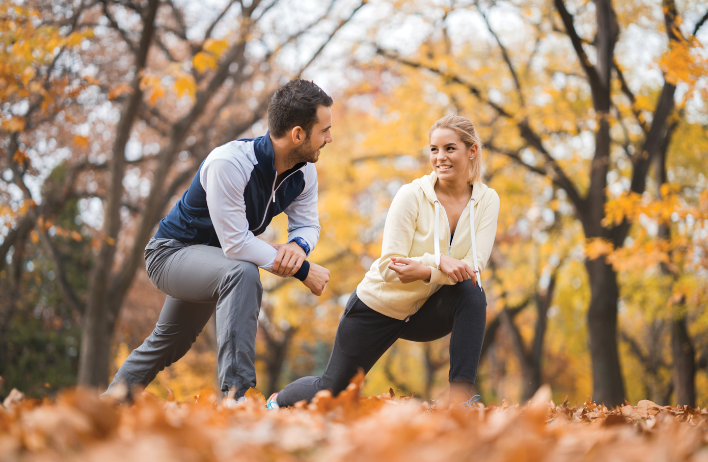 A couple do lunges together outdoors in autumn.