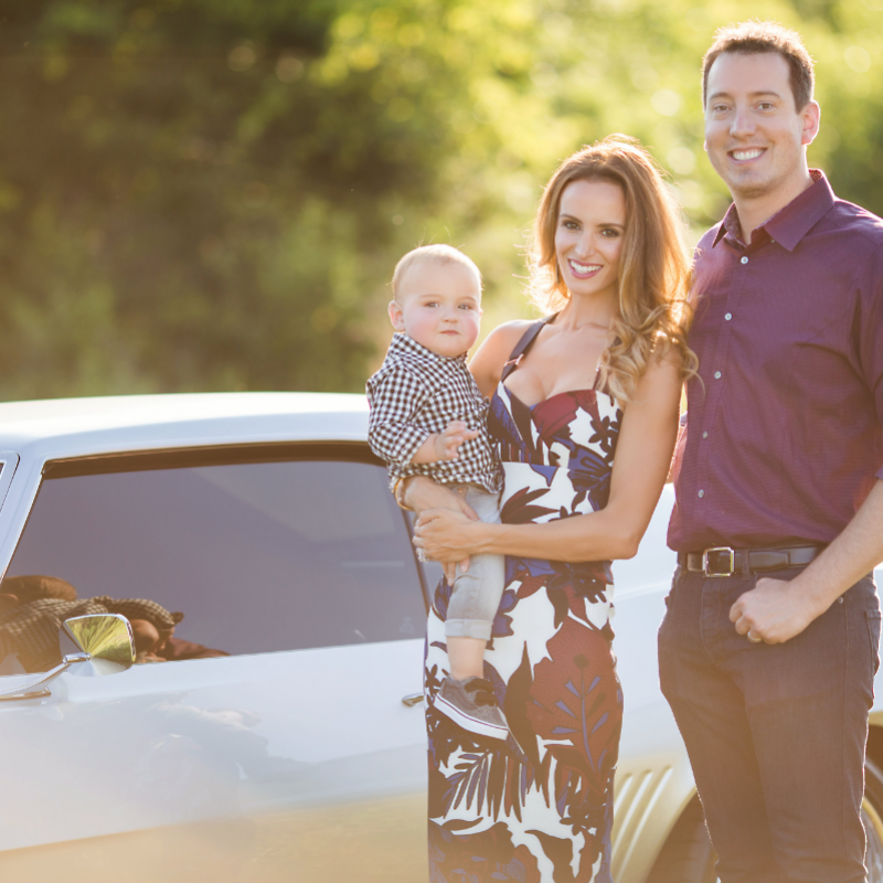 kyle and samantha busch next to muscle car holding child 