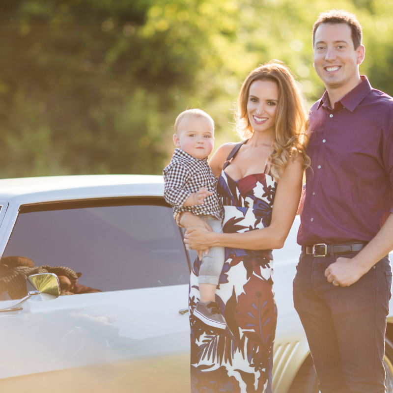 kyle and samantha busch next to muscle car holding child